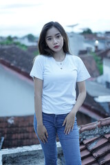 Stylish blonde girl wearing a white shirt on the roof of the building with a view of the clear sky. female t-shirt models for mockups and templates.