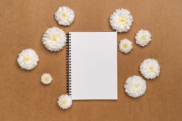 Notebooks and flowers-  notebook and white flowers on brown paper