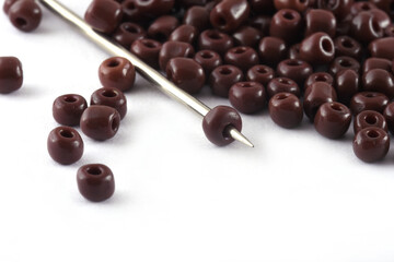 Beads spread on white background with needle. Beads with needle . Close up, macro,It is used in finishing fashion clothes. make bead necklace, beads for woman of fashion,Bead Crochet. Daily Beading.