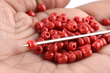 Close up photo of a woman's hand nailing beads on a needle.Beads with needle. macro,used in finishing fashion clothes. make bead necklace, beads for woman of fashion,Bead Crochet. Daily Beading.