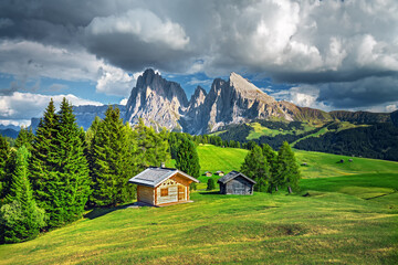 Fototapeta na wymiar Famous Alpe di Siusi - Seiser Alm with Sassolungo - Langkofel mountain group in background at sunset. Wooden chalets in Dolomites, Trentino Alto Adige region, South Tyrol, Italy