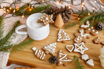 Christmas star gingerbread cookie on aromatic coffee at pine cones, fir branches and warm lights