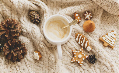 Warm coffee on background of cozy knitted sweater with christmas gingerbread cookies