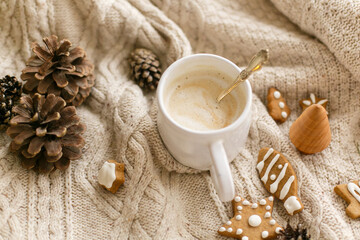 Warm coffee on background of cozy knitted sweater with christmas gingerbread cookies