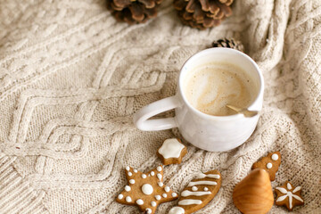 Warm coffee on background of cozy knitted sweater with christmas gingerbread cookies