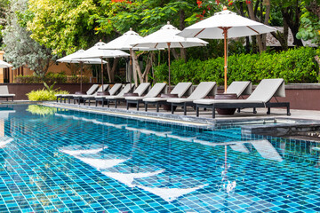 White umbrella and outdoor beds next to swimming pool