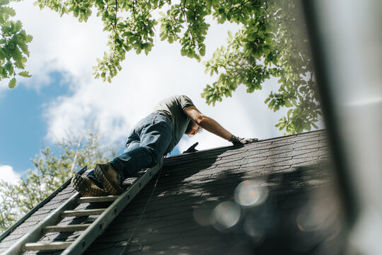 Low Angle View Of Man Against Climbing On Roof