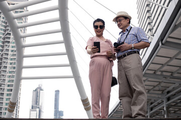 Senior Asian couple selfie by mobile outdoors.