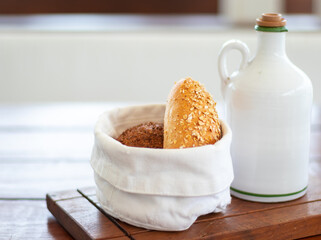 homemade bread in a white sack with a bottle of olive oil on a wooden table