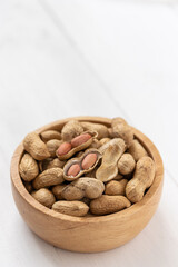 Portrait view of Peanuts in a wooden bowl on white background,