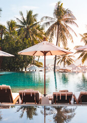 White umbrella and outdoor beds next to swimming pool