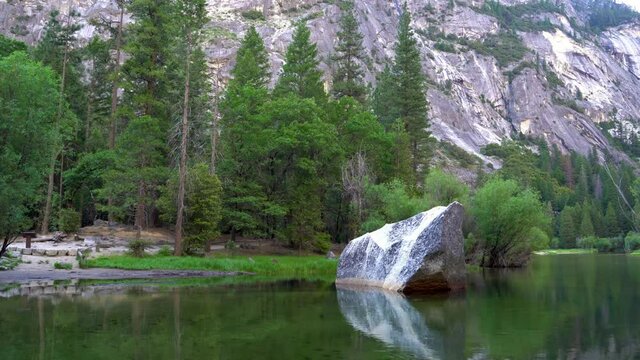 Yosemite National Park reflection in Merced River of Yosemite waterfalls and beautiful mountain landscape in California USA. amazing rocky hills and pine trees on the other side of mirror lake.
