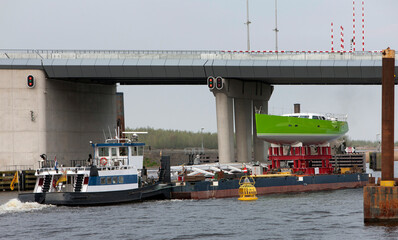 Transport of a super sailing yacht on a pontoon with tugboats. Shipbuilding industry. Ramspol viaduct. Noordoostpolder. Netherlands. Zwarte water river.