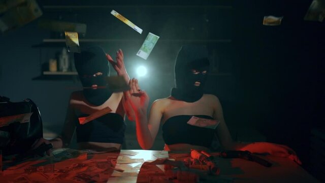 The girls robbers in a black masks and sexy suit with pistols and cash. Bag with money