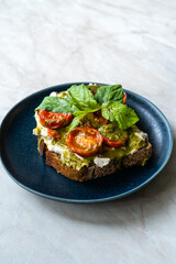 Healthy Toast Tartine with Cream Vegan Cashew Cheese Truffle Flavored, Pesto Sauce and Cherry Tomatoes.