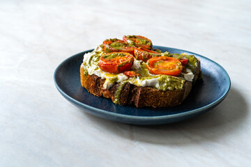 Healthy Toast Tartine with Cream Vegan Cashew Cheese Truffle Flavored, Pesto Sauce and Cherry Tomatoes.