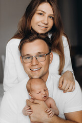 Overjoyed parents with newborn baby girl, loving dad gently hold little daughter in arms, beautiful mother hug caring father, smiling, enjoy happy moments, young family concept