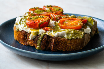 Healthy Toast Tartine with Cream Vegan Cashew Cheese Truffle Flavored, Pesto Sauce and Cherry Tomatoes.