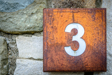 Rusted squared house sign with number three 