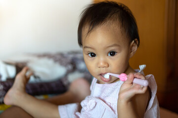 11-month-old girl practicing a toothbrush by herself from her mother's teaching.