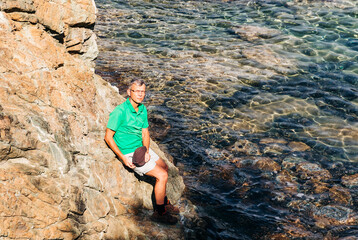 Mature man on cliffs of Mediterranean Sea