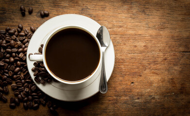 cup of coffee with beans on wooden table