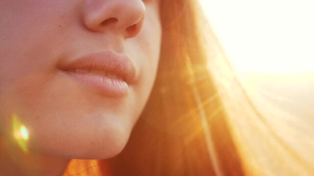 dream face of a beautiful girl lips hair fluttering in the wind in the sunlight dream of happiness. people in the park concept. model close-up face lips strong wind hair swaying in the park