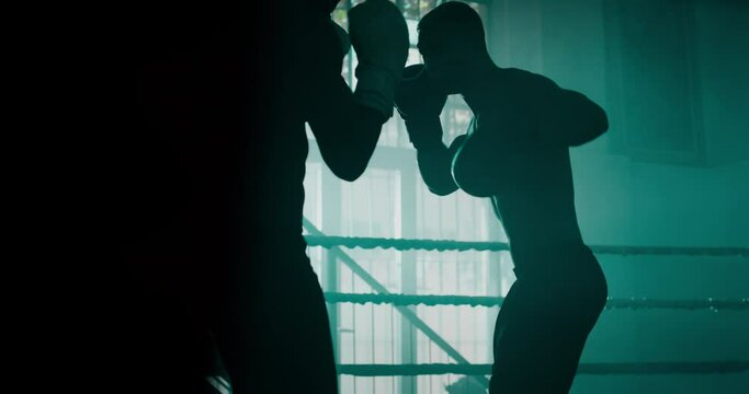 Cinematic slow motion shot of two professional young muscular shirtless male boxers are fighting  in a boxing ring.