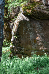 large geometric stone rocks overgrown with light green yellow moss in light of sun with shadows in grass. Krasnoyarsk pillars, nature park