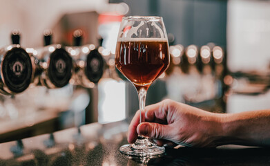 man holds a glass of beer in his hand at the bar or pub