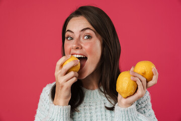 Image of happy beautiful girl holding and eating lemons