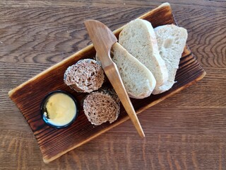 slices of bread and butter on a wooden plate on a wooden serve table in a restaurant 
