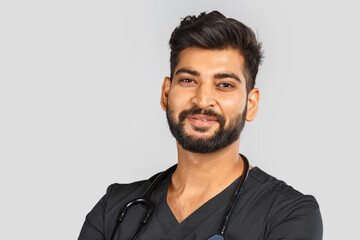 Obraz premium smiling indian doctor or surgeon in black uniform with stethoscope on gray background