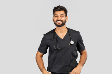 smiling indian doctor or surgeon in black uniform with stethoscope on gray background