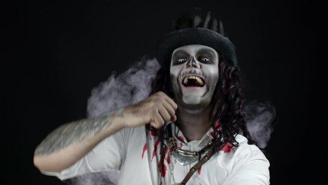 Creepy man with skeleton Halloween makeup in bloody shirt. Guy listening music, dancing, celebrating