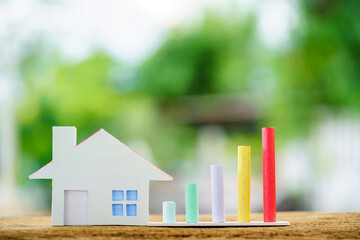 House model and bar graph with growing value put on the wood in the public park, Loan and business investment for real estate concept.