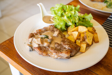 T-bone steak, a prepared piece of grilled T-bone steak brown sauce with mashed potato and vegetable on dining table