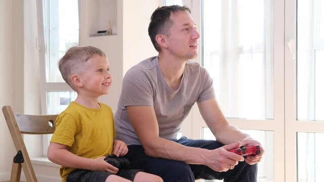 Father and son playing videogames together with video game controllers