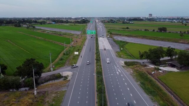 Cars Driving On The Ratchaphruek Road By The Lush Green Fields In The Countryside Of Bangkok, Thailand. - aerial drone shot