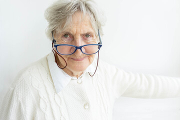 Gray hair senior lady in glasses on white wall background