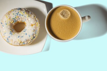 Close up view of cup of coffee and red donut isolated on blue  background. Food and drink concept.