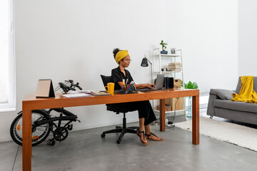 Shot of young latin woman working at home office with laptop and documents