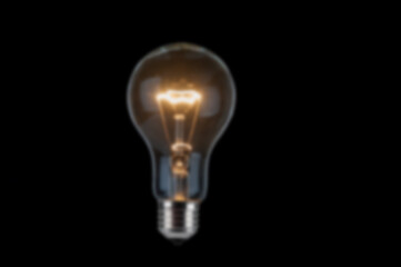 Blurred image of glowing light bulb on black background