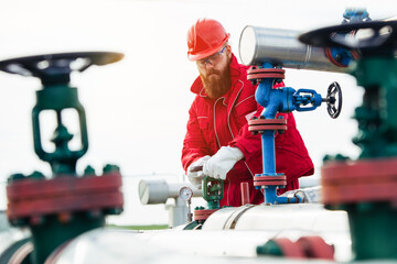 Oil worker turning valve on oil rig