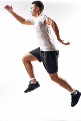 athlete man in sneakers shorts and a t-shirt on a light background and running to the side in full growth