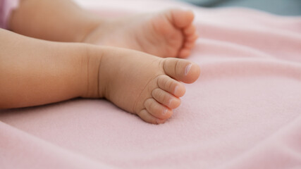 Infant baby legs on pastel pink background, closeup of newborn barefeet
