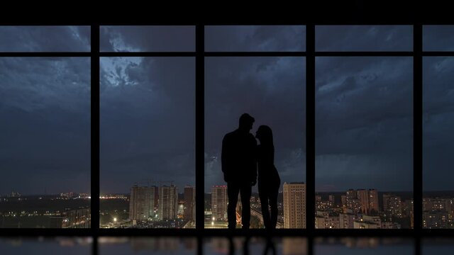 The couple stand near the big windows on the rainy city background. time lapse