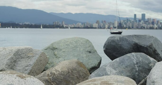 Rocks with cityscape and a sailboat in the background.