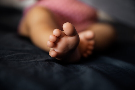 Adorable baby feet on dark background, infant barefeet in a selective focus, babyhood concept - Image