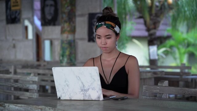 Young freelancer girl typing on mobile at restaurant outside, Bali